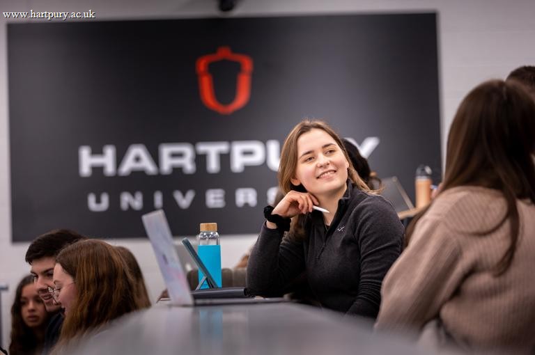 Image of students sat in a lecture theatre with a student smiling at other nearby students