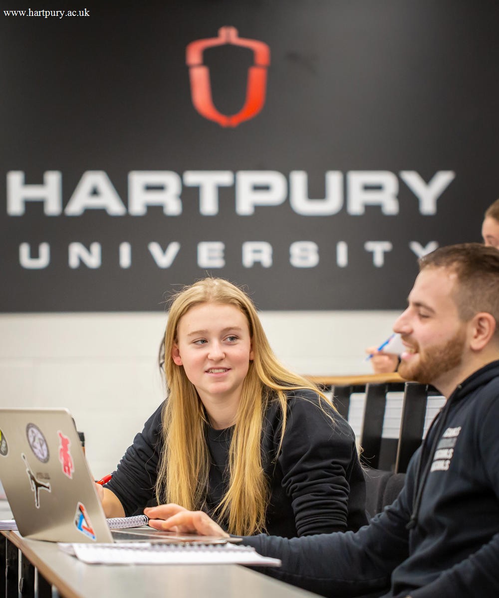 Image of students sat in a lecture theatre with their laptop and notepad
