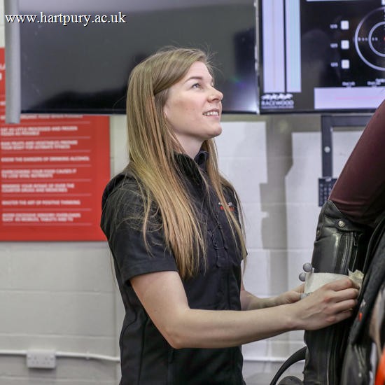 Lady Helping A Rider On Horse Simulator